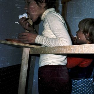 Two people eating together at a wooden table.