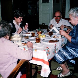 Family gathering enjoying birthday cake indoors.