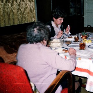Family gathering enjoying birthday cake indoors.