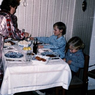 Family meal scene with woman serving children at table.