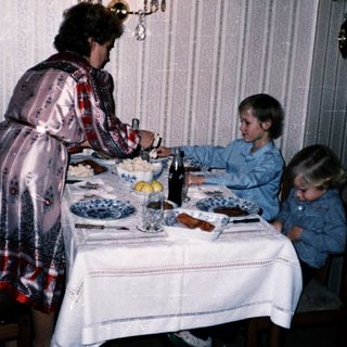Family meal scene with woman serving children at table.
