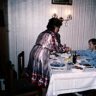 Family meal scene with woman serving children at table.