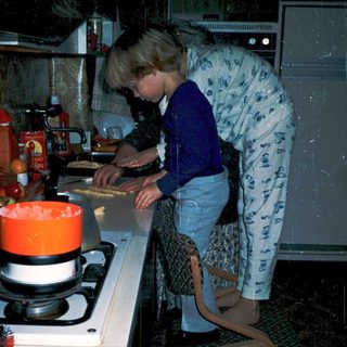 Woman cooking pancakes on gas stove.