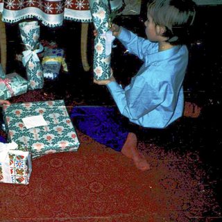 Two children opening wrapped holiday gifts.