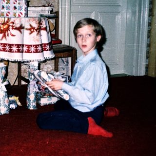 Two children opening Christmas presents indoors.