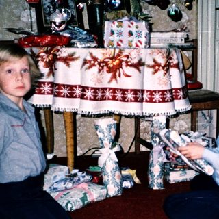 Two children opening Christmas presents indoors.