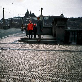 People standing on a bridge with historic cityscape background.
