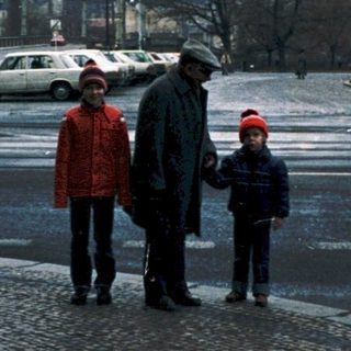 Family crossing street in city with historic background.
