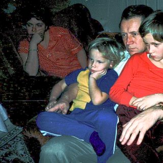 Family watching television indoors, mid-1970s.