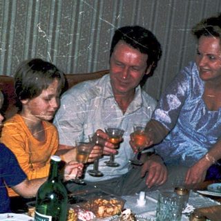 Family gathering around a table with drinks and food.