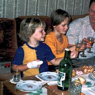 Family gathering around a table with drinks and food.