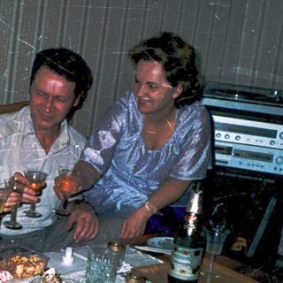 Family gathering around a table with drinks and food.