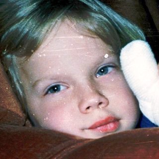 Young child with bandaged arm peeking from behind.