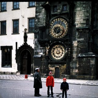 Famous Prague Astronomical Clock with three people standing nearby.