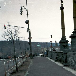Two people walking on a bridge near historic city.
