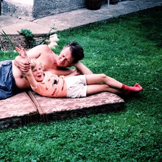 Two people relaxing on a wooden bench outdoors.