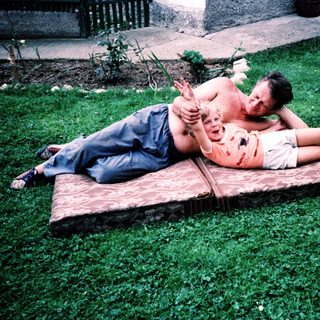 Two people relaxing on a wooden bench outdoors.