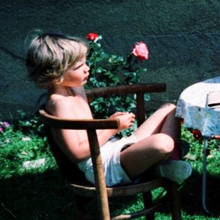 Two people, including a child, dining outdoors under umbrella.