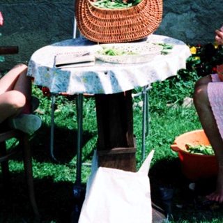 Two people, including a child, dining outdoors under umbrella.