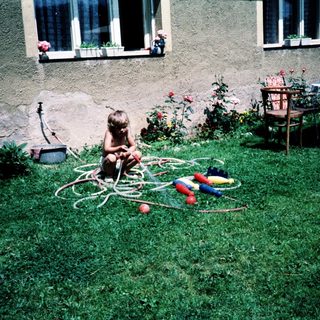 Child playing with garden hose toys outdoors.