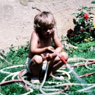 Child playing with garden hose toys outdoors.