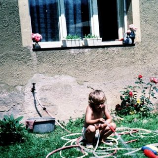 Child playing with garden hose toys outdoors.