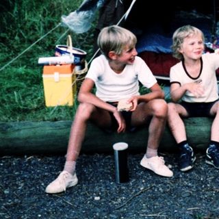 Family camping under tents in forested area.