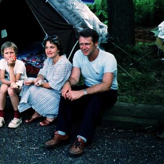 Family camping outdoors under a tent.