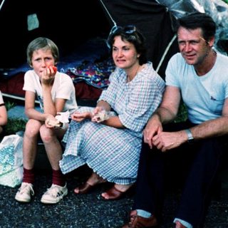 Family camping outdoors under a tent.