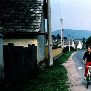 Two children riding bikes down a quiet rural road.