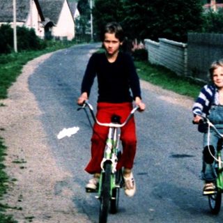 Two children riding bikes down a quiet rural road.
