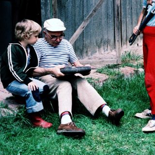 Three generations outdoors, reading and playing.