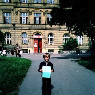 Boy holding large poster outside historic building.
