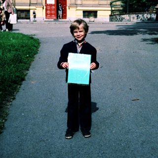 Boy holding large poster outside historic building.
