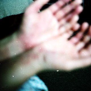 Blurred hands reaching upward in dim light.