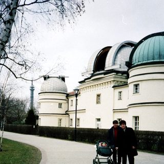 Family pushing stroller near observatory buildings.