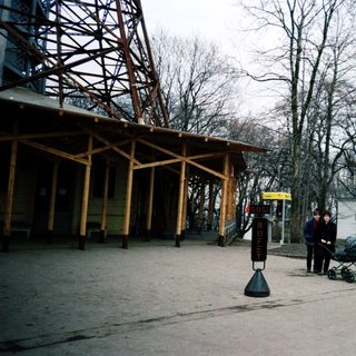 Urban park area with stroller, bare trees, and shelter.
