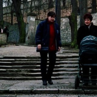 People walking up stone stairs near a high wall.