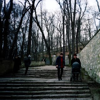 People walking up stone stairs near a high wall.