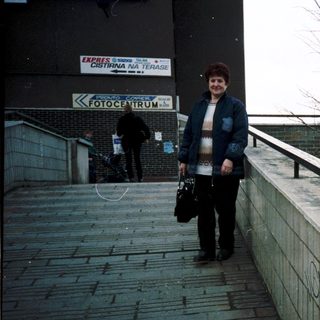 Woman walking outdoors near "Fotocentrum" storefront.