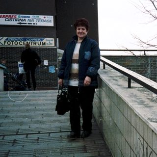 Woman walking outdoors near "Fotocentrum" storefront.