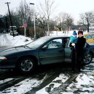 Family standing by snow-covered car in winter.