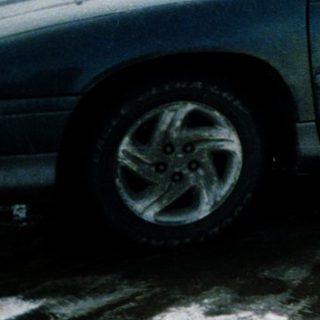 Family standing by snow-covered car in winter.
