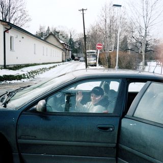 Person waving from car on snowy road.