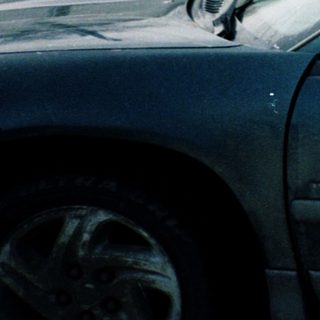 Person waving from car on snowy road.