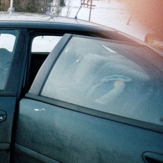 Person waving from car on snowy road.