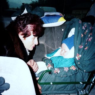 Woman caring for baby in car stroller.