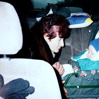 Woman caring for baby in car stroller.