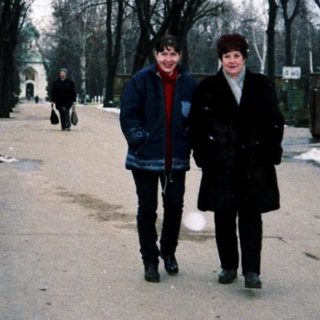 Two people walking in a cemetery during winter.