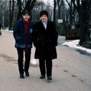 Two people walking in a cemetery during winter.